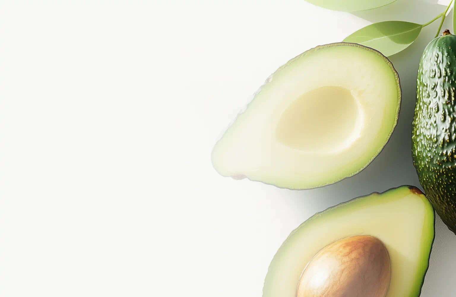 Whole and halved avocados with green leaves