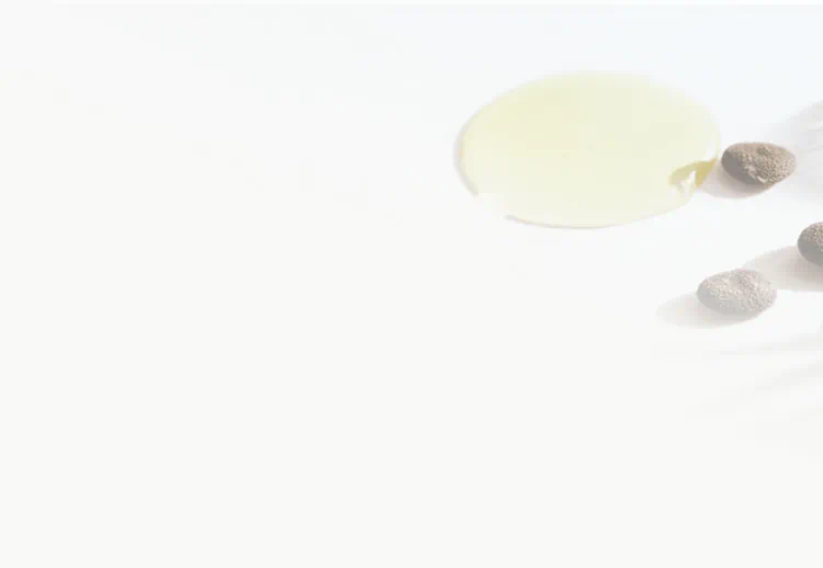 Babchi seeds and light-colored oil on a white surface