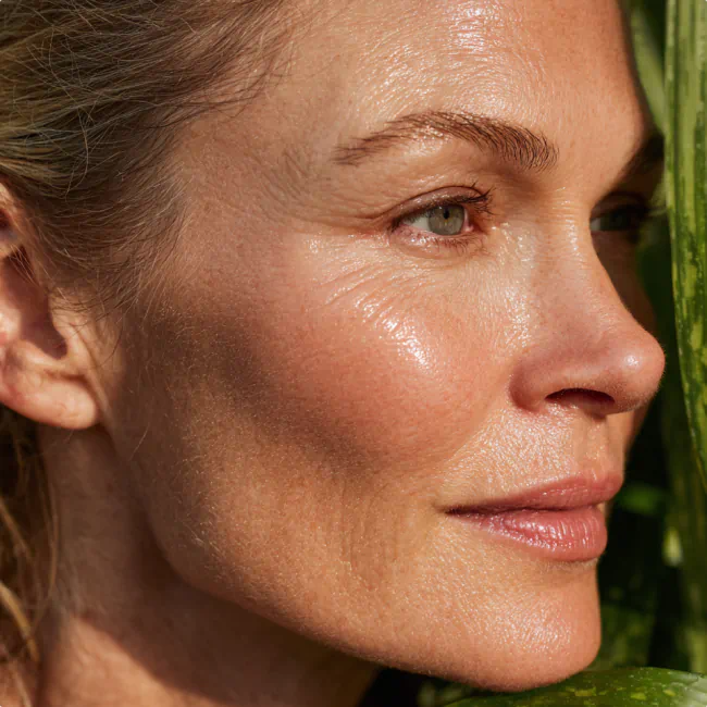 Close-up of a woman with glowing, moisturized skin in natural light