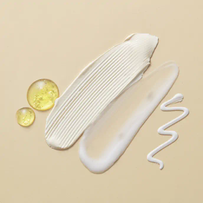 Swatches of cream, lotion, gel, and oil on a beige surface