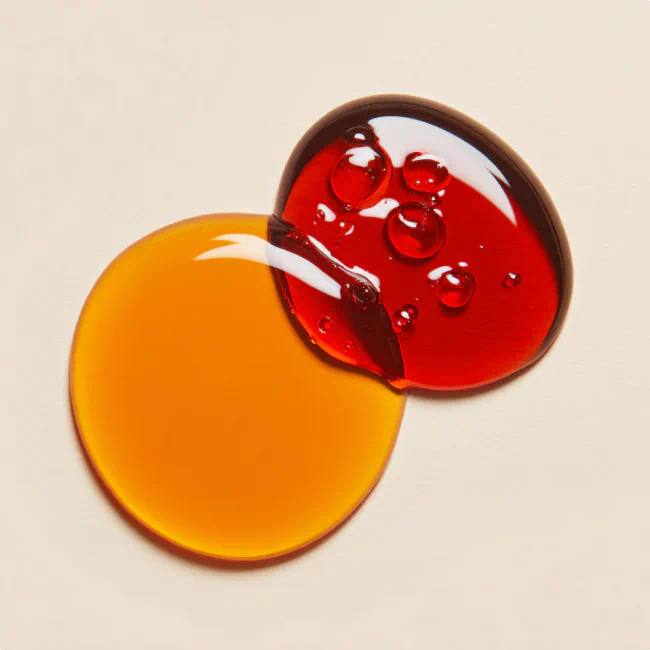 Overlapping drops of orange and red skincare oils