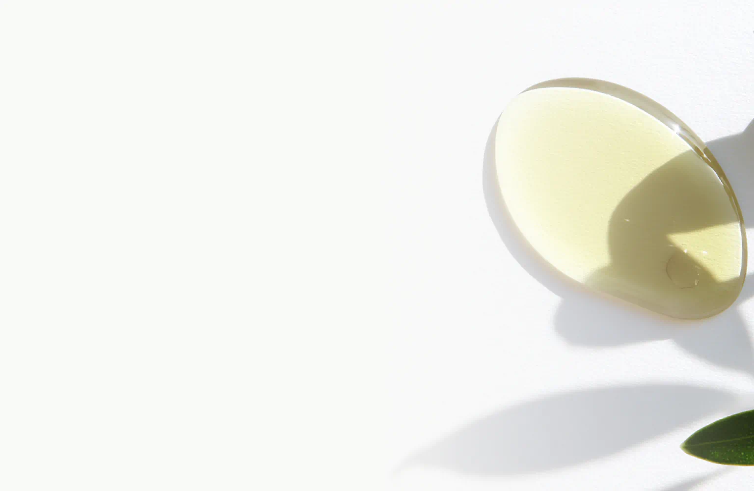 Golden drop of Vitamin E oil on a white surface