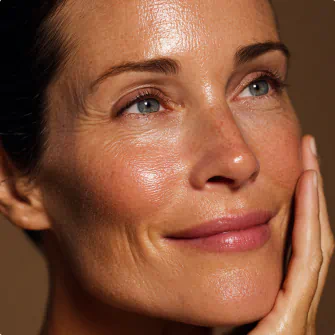 Woman gently touching her face, showcasing luminous and healthy skin